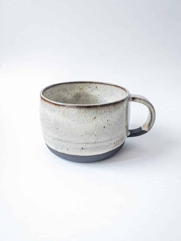 stor keramisk mugg med handtag av mörk lera i vitt