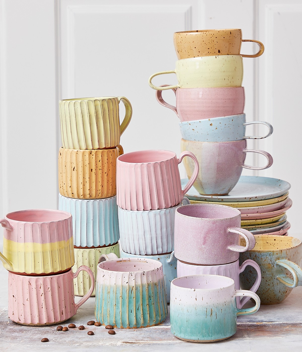 keramiska muggar och muggar med handtag och koppar utan dem, rosa keramiska muggar, karamellmuggar i pastell.