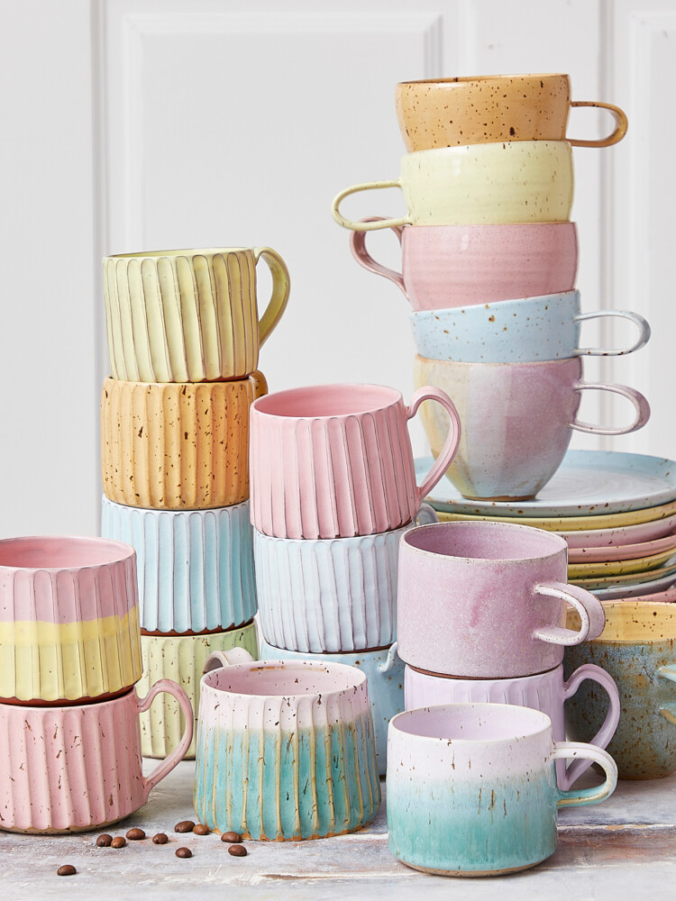 keramiska muggar och muggar med handtag och koppar utan dem, rosa keramiska muggar, karamellmuggar i pastell.
